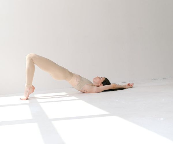 Woman performing a calm yoga stretch in a gray and white studio.